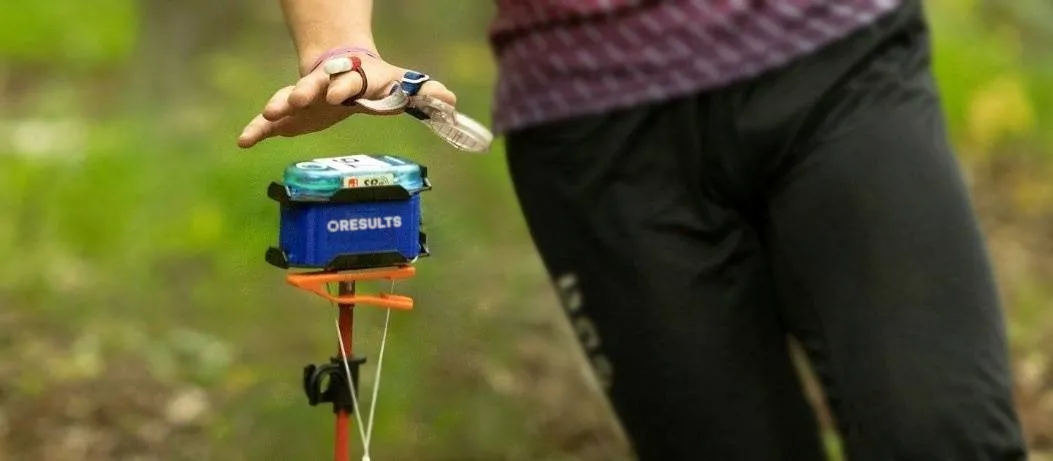 A Bluebox on a control stand in the forest, with the SI station on top of it and a runner punching